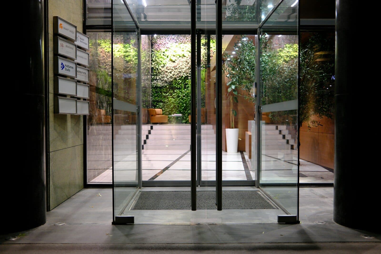 Modern building entrance with glass doors and a green wall